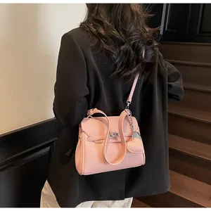 Detail of pink lychee leather handbag with heart charm and silver metal twist lock