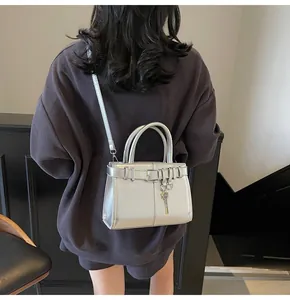 Détail d'un sac à main argenté métallisé avec boucle décorative et breloque clé sur bandoulière