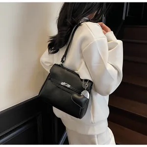 Close-up of black lychee grain leather handbag featuring silver lock and heart charm