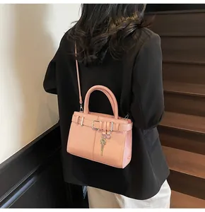 Détail du sac à main en cuir rose avec breloque clé dorée et lanière à boucle