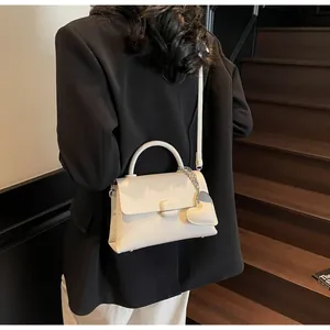 Close-up of white lychee pattern leather handbag with heart-shaped charm and round handle