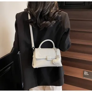 Rear view of a model carrying a white lychee grain crossbody bag with a heart charm