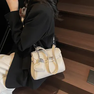 Beige lychee pattern leather handbag with heart charm on wooden stairs background