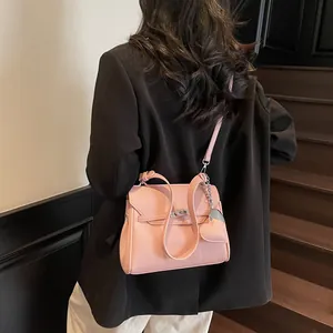 Pink lychee textured Kelly style handbag with heart charm shown on model in modern setting