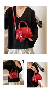 Detail of red patent leather mini Boston bag with heart charm and embossed texture