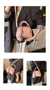 Detail of light pink bowling bag featuring a heart charm and embossed brand text on PU leather