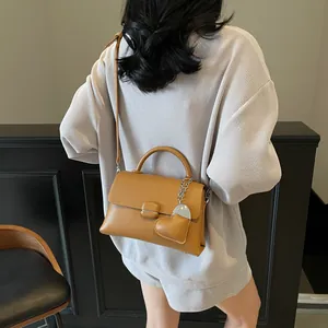 Elegant brown leather crossbody bag with top handle and metal square buckle