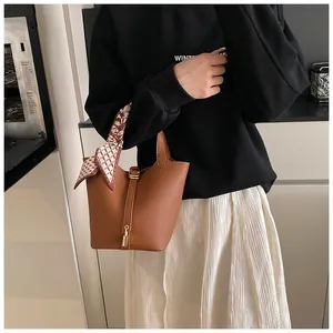 Detailansicht der braunen Bucket Bag aus Leder mit Seidenschal und goldenem Vorhängeschloss