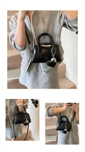 Detail of black glossy patent leather bowling bag with heart charm and shoulder strap