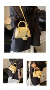 Detail of pale yellow patent leather boston bag with embossed letters and heart charm