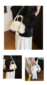 Detail of white PU leather handbag with embossed lettering and heart charm attachment
