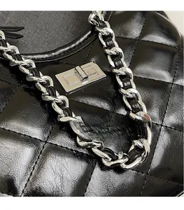 Detailed close-up of black quilted leather texture and silver chain strap with turn-lock