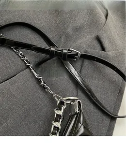 Detailed macro view of adjustable black quilted bag strap with silver metal eyelets and chain