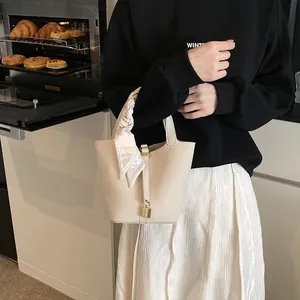 Schicke beige Eimertasche aus strukturiertem Leder mit Seidenschal und goldenem Schloss
