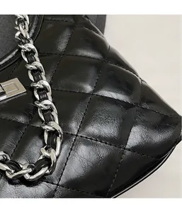 Detail of black quilted leather texture with silver metal twist lock and chain strap