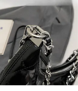 Detail of silver chain and metal buckle on black quilted leather shoulder bag