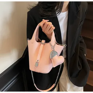 Close-up of pink litchi leather bucket bag featuring a cute heart-shaped pendant
