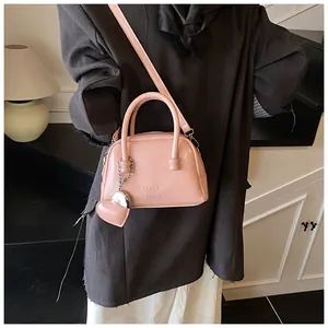 Close-up of pink leather handbag with embossed letters and heart-shaped charm accessory