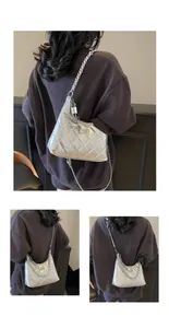Detail of silver quilted bucket bag featuring a metal turn-lock and chain strap