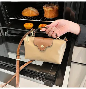 Mini crossbody bag detail with khaki body and brown leather handles in lifestyle setting