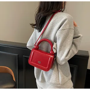 Détail du sac à main en cuir verni rouge avec connecteurs de poignée en métal sphérique
