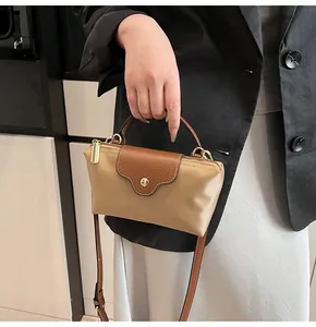 Detail of contrast stitching and polished gold hardware on the khaki handbag strap