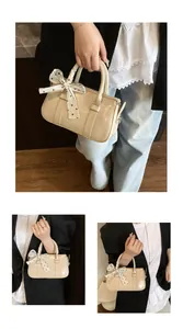 Detail of a beige glossy mini Boston bag featuring double handles and polka dot silk scarf