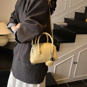 Vintage beige top handle bag with heart charm shown in a lifestyle indoor setting