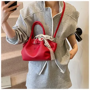 Close-up of red pebbled leather bag featuring a pearl and lace bow charm detail