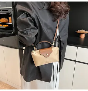 Mini beige nylon tote bag with brown leather flap shown worn crossbody on black blazer