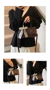 Detail of dark brown leather Boston bag with polka dot scarf on minimalist stairs