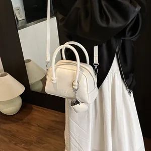 Minimalist white leather Boston handbag with detachable strap and heart pendant detail