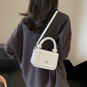 Petit sac bandoulière blanc minimaliste en cuir avec poignée et finitions argentées