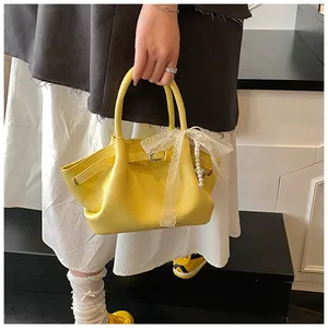 Detail of yellow pebbled leather tote bag with lace bow and pearl charm ornament