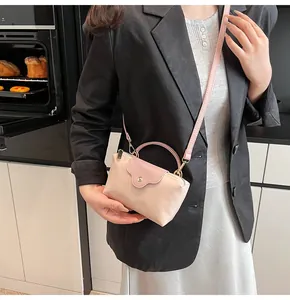 Detail of beige and pink nylon handbag with leather flap held by a model in a modern kitchen