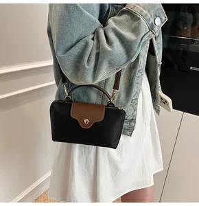 Detailed view of nylon dumpling bag with leather flap and strap worn by a model
