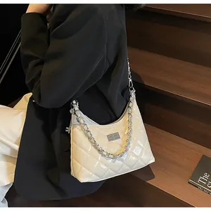 Détail du sac seau en cuir matelassé avec chaîne argentée sur mannequin en costume noir