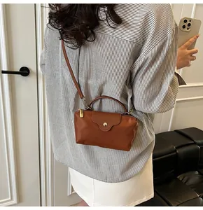 Brown nylon crossbody bag with golden snap button shown in a lifestyle model shot