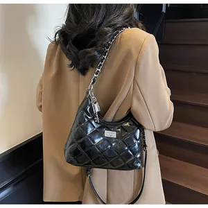 Sac seau matelassé noir brillant avec chaîne argentée porté par un mannequin