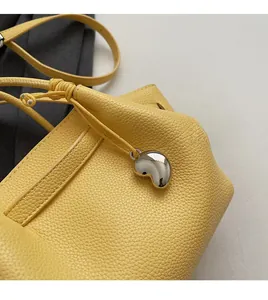 Detail of yellow lychee grain leather bag with fine stitching and silver heart pendant