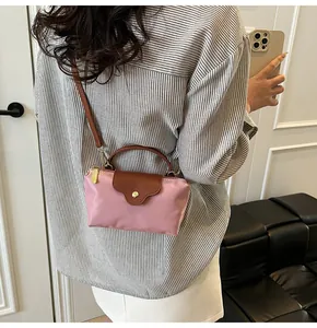 Pink nylon crossbody bag with brown leather handles and flap shown on a model's back