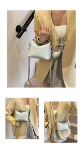 Detail showing litchi texture leather handbag with heart-shaped charm and silver zippers