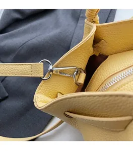 Detail of silver metal clasp on yellow lychee texture leather shoulder bag