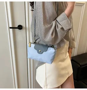 Detailed view of mini crossbody bag with contrasting flap worn by a model in casual attire