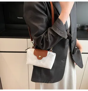 Minimalist white nylon crossbody bag with brown leather flap and gold magnetic clasp