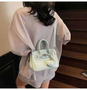 Detail of mint green patent leather kelly bag with heart charm on wooden stairs