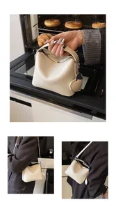 Detail of cream leather square handbag with adjustable strap and heart-shaped charm