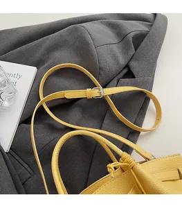 Detail of yellow lychee grain leather bucket bag featuring a drawstring and adjustable strap