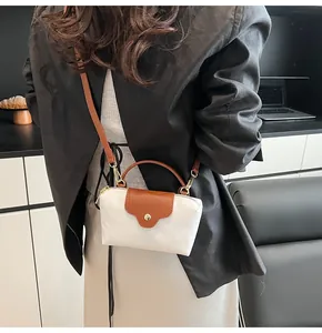 Detail showing contrast color crossbody bag with brown leather flap and gold hardware