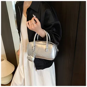 Silver metallic bowling bag with heart charm shown in a cozy indoor fashion setting